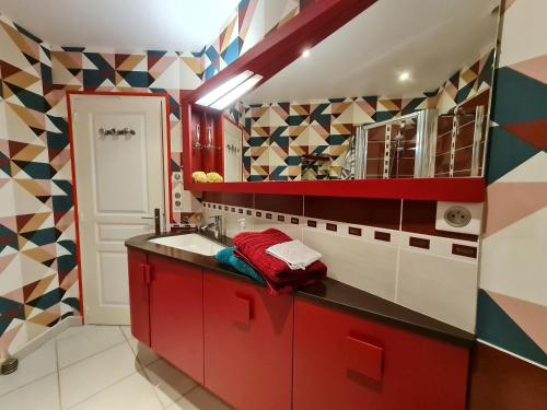 una cocina con armarios rojos y azulejos coloridos en Guestroom Bonnée, 1 pièce, 2 personnes - FR-1-590-287, en Bonnée