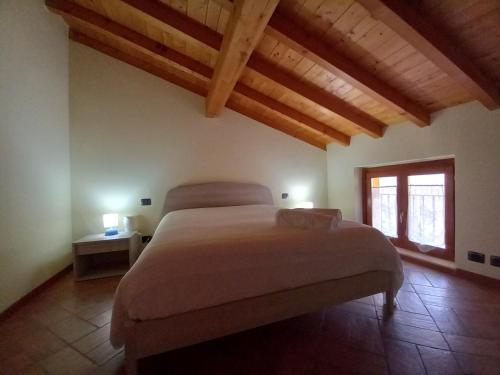 Un dormitorio con una cama grande en una habitación con techos de madera. en CASA VACANZE TANIA, en Somendenna