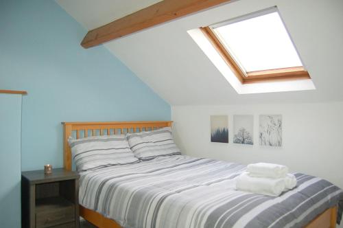 a bedroom with a bed with white sheets and a skylight at Idris View Family Holiday Home in Tywyn