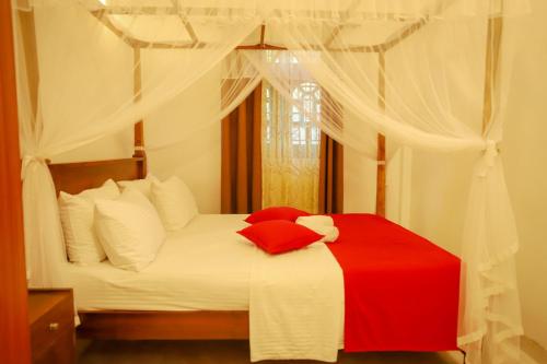 a bedroom with a bed with a red and white blanket at Punida villa in Matara
