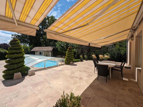 un patio avec une table et des chaises et une piscine dans l'établissement Maison Spacieuse en Village, Équipée et Confortable, avec Accès Rivière et Garage. - FR-1-611-93, à Louvemont