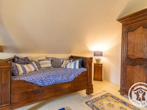 a bedroom with a wooden bed with pillows at Évasion Romantique au Prieuré avec Jardin en Anjou, Petit-Déjeuner Inclus - FR-1-622-63 in Méa