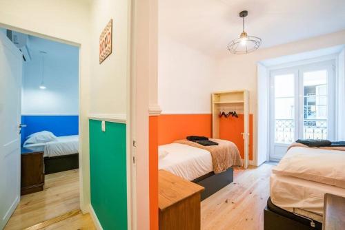 twee bedden in een kamer met oranje en groen bij Moments from Baixa and Alfama by LDapartments in Lissabon