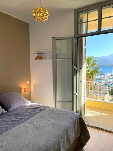 une chambre avec un lit et une porte coulissante en verre dans l'établissement Superbe appartement vue mer - terrasse et parking, à Calvi