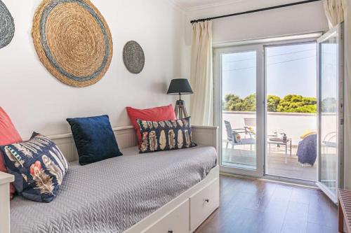 a room with a bed with pillows and a balcony at Vita Portucale ! Costa Caparica Duplex Sea View in Almada