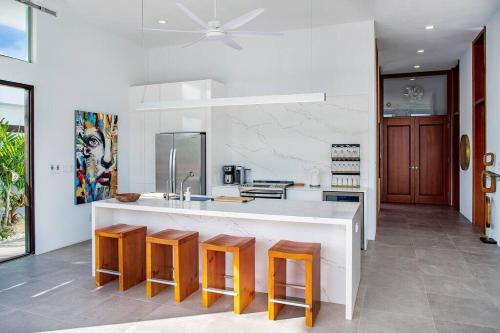 a kitchen with a white counter and wooden stools at Beachside 4 Bedroom Villa with Pool and Resort Amenities - White Villas - v9 in Long Bay Hills