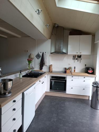 une cuisine avec des armoires blanches et un four à plaques de cuisson dans l'établissement Location maison de ville à 5 minutes du Puy du Fou !, à Chambretaud