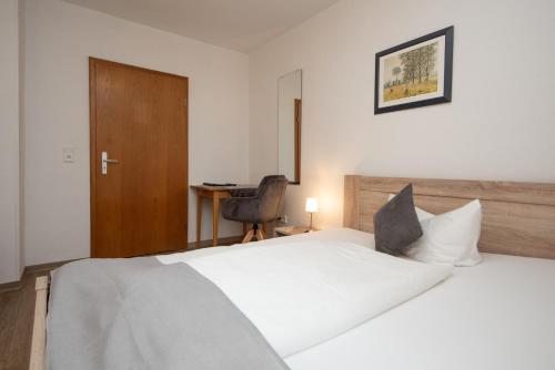 a bedroom with a white bed and a desk at Neckarperle in Edingen-Neckarhausen