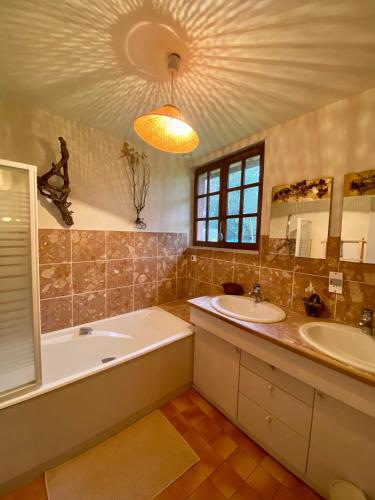 La salle de bains est pourvue de 2 lavabos, d'une baignoire et d'un grand miroir. dans l'établissement Superbe Maison normande - Piscine, à Saint-Pierre-des-Ifs