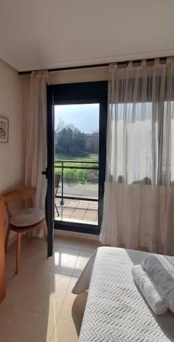 a bedroom with a bed and a large window at Gestiona2R - Apartamento para 2 con piscina in Posada de Llanes