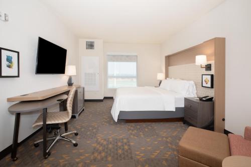 a hotel room with a bed and a desk and a computer at Holiday Inn Glendale - Stadium & Ent Dist in Glendale