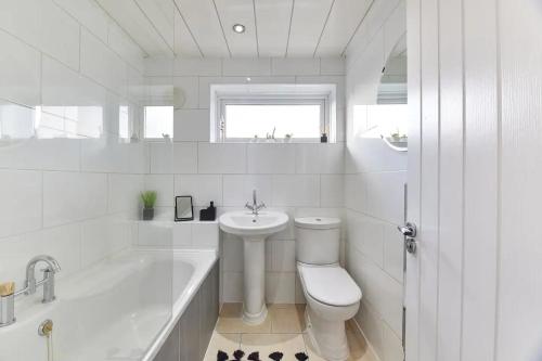 a white bathroom with a toilet and a sink at Cosford House - 3BR House in in Kenton