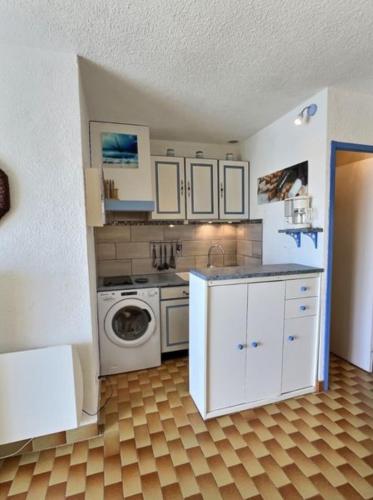 une cuisine avec des armoires blanches et une laveuse et une sécheuse dans l'établissement Noug, à Valras-Plage