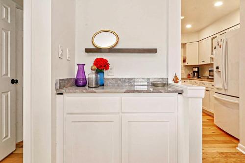 a kitchen with white cabinets and a purple vase with flowers at Tranquility with Hot Tub in Virginia Beach