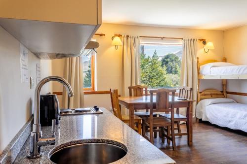 a kitchen with a sink and a table and a bedroom at Hotel Kallfu by Nordic in Caviahue