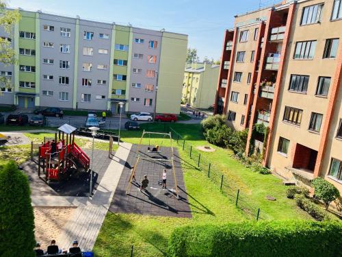 la gente jugando en un patio de juegos en un parque con edificios en One bedroom studio apartment in Ikskile en Ikšķile
