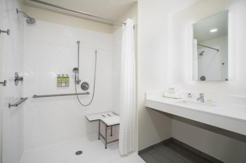a white bathroom with a shower and a sink at Holiday Inn Glendale - Stadium & Ent Dist by IHG in Glendale