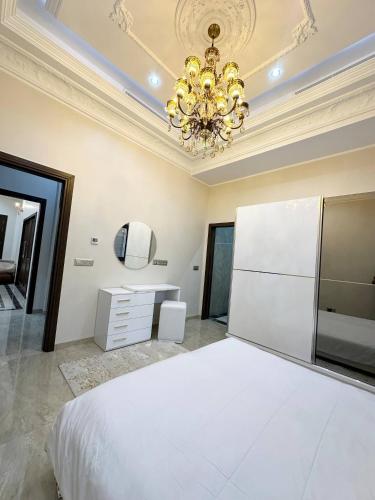 a bedroom with a white bed and a chandelier at Luxury Villa, Central Ac, Bbq, Ideal For Events in Rejiche