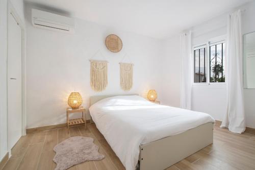 a white bedroom with a bed and two lamps at Cayo Coco Yodo - 2 min walk to the beach in Torreguadiaro
