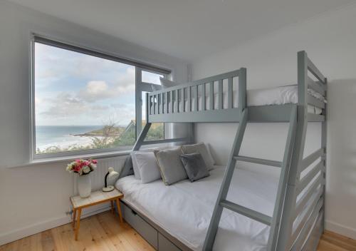 a bedroom with a bunk bed and a window at Trecarrack Carthew Way in St Ives
