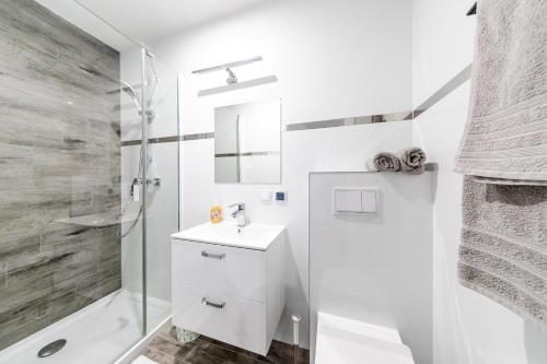 a white bathroom with a sink and a shower at U Wandy in Trzęsacz