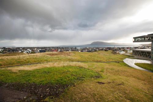 a view of a field with a town in the background at 62N Guesthouse Marknagil in Tórshavn