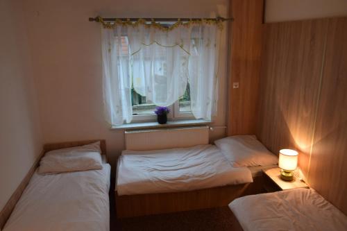 two beds in a small room with a window at Apartament Czos Kominek Premium in Mrągowo