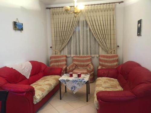 ein Wohnzimmer mit zwei roten Sofas und einem Tisch in der Unterkunft Tafilaj Apartments in Durrës