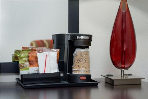 a coffee maker on a table next to a red vase at Stay 2Night Chattanooga Hamilton Place in Chattanooga