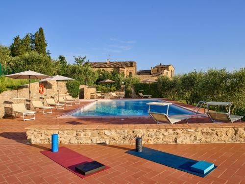 basen z leżakami i parasolami obok niego w obiekcie Agriturismo Podere Cortilla w mieście Volterra