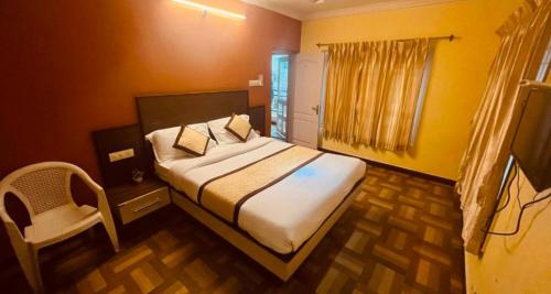 een slaapkamer met een bed en een stoel erin bij MR Resort Room type in Ooty
