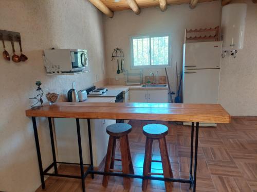 a kitchen with a wooden counter and two stools at Vista Norte departamento in Las Heras