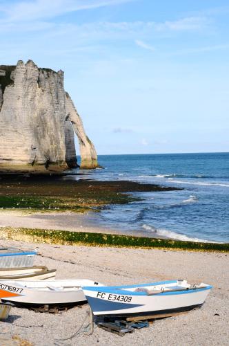 trois bateaux assis sur la plage près de l'eau dans l'établissement Maison cosy vue mer à 50m de la plage, à Étretat