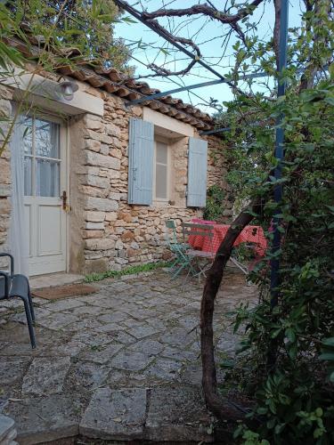 une maison en pierre avec une porte blanche et une chaise dans l'établissement Sous la vigne, à Rustrel