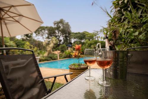 two glasses of wine sitting on a table next to a pool at Pousada das Brumas in Brumadinho