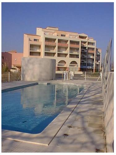 une piscine en face d'un grand bâtiment dans l'établissement Les Terrasses du Grand Bleu,6 pers, parking, piscine, au Cap d'Agde