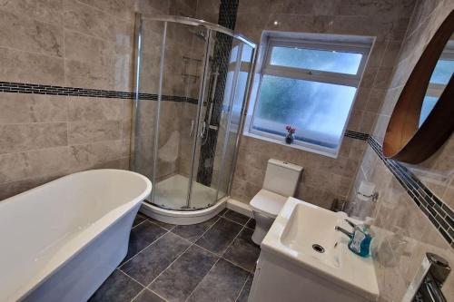 een badkamer met een bad, een douche en een wastafel bij Forest view cottage in Nottingham