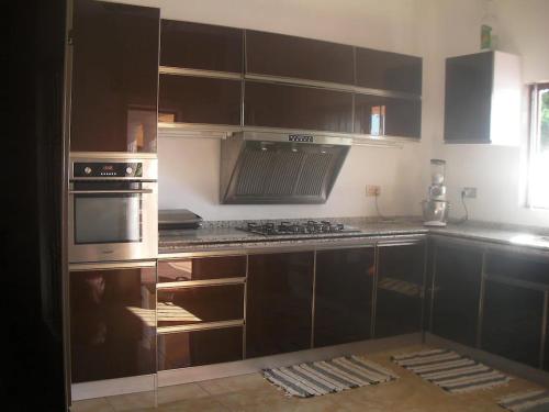 a kitchen with brown cabinets and a stove top oven at Belle villa , pieds dans l'eau avec piscine in Terre Rouge