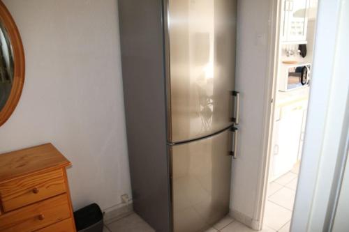 - un réfrigérateur en acier inoxydable dans une cuisine à côté d'une porte dans l'établissement Appartement 307, Héliopolis K au village naturiste, au Cap d'Agde