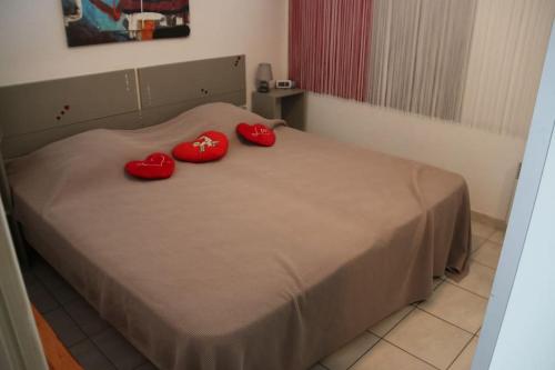 - 2 oreillers rouges sur un lit dans l'établissement Appartement 307, Héliopolis K au village naturiste, au Cap d'Agde
