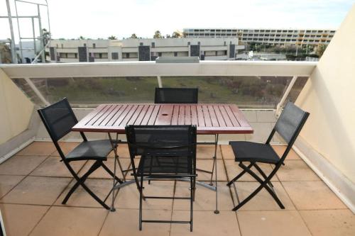 d'une table en bois et de quatre chaises sur un balcon. dans l'établissement Appartement 307, Héliopolis K au village naturiste, au Cap d'Agde