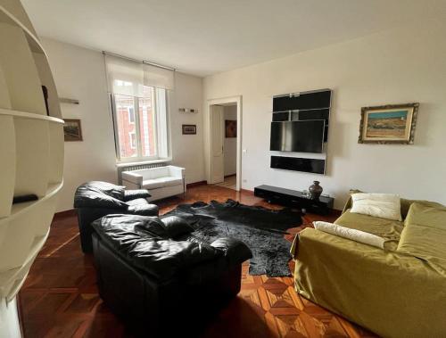 ein Wohnzimmer mit einem schwarzen Ledersofa und einem TV in der Unterkunft Appartamento nel cuore di Asti in Asti