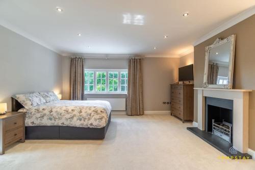 1 dormitorio con cama, chimenea y espejo en Luxe Home with Hot Tub, Cinema, Games Room & Sauna en Buckinghamshire