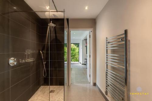 La salle de bains est pourvue d'une douche et d'une porte en verre. dans l'établissement Luxe Home with Hot Tub, Cinema, Games Room & Sauna, à Buckinghamshire