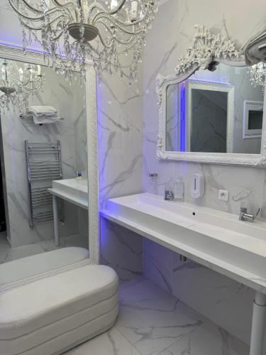 une salle de bain blanche avec deux lavabos et un miroir dans l'établissement La suite santorini, à Villemomble