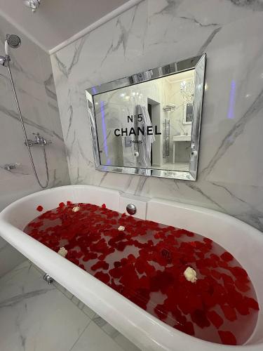 La salle de bains est pourvue d'une baignoire remplie de pétales rouges. dans l'établissement La suite santorini, à Villemomble
