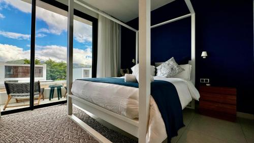1 dormitorio con 1 cama con paredes azules y balcón en Villa familiale avec piscine en Tamarin