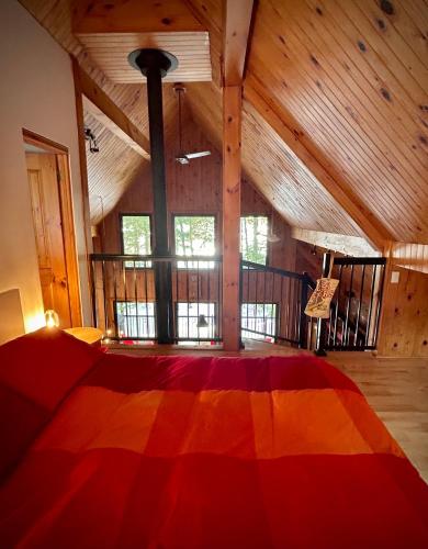 a bedroom with a colorful bed in a room with wooden ceilings at Winter Lakefront Chalet - Serendipity Hideaway - Ski, Skate, Snowshoes & Relax by the Cozy Fire in Chertsey