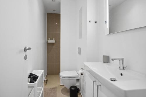 a white bathroom with a toilet and a sink at Moderne Lejlighed i Aalborg Vestby - 1 BR in Aalborg