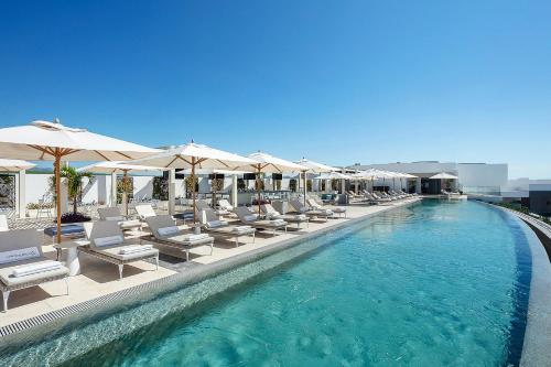 a swimming pool with lounge chairs and umbrellas at Residential Retreat 3 Bedroom Suite Ocean Front Garza Blanca Los Cabos Resort & Spa in Cabo San Lucas